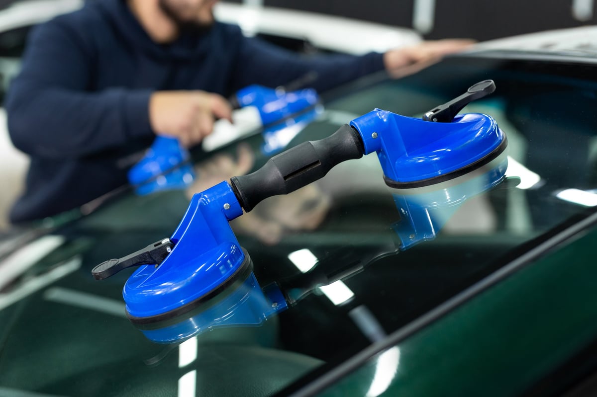 Close-up of car glass being handled with professional suction cups
